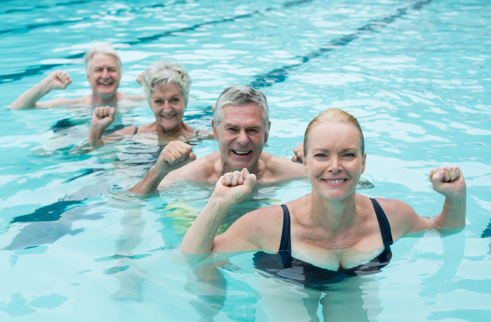 A group of older adults having fun during aquatic therapy.