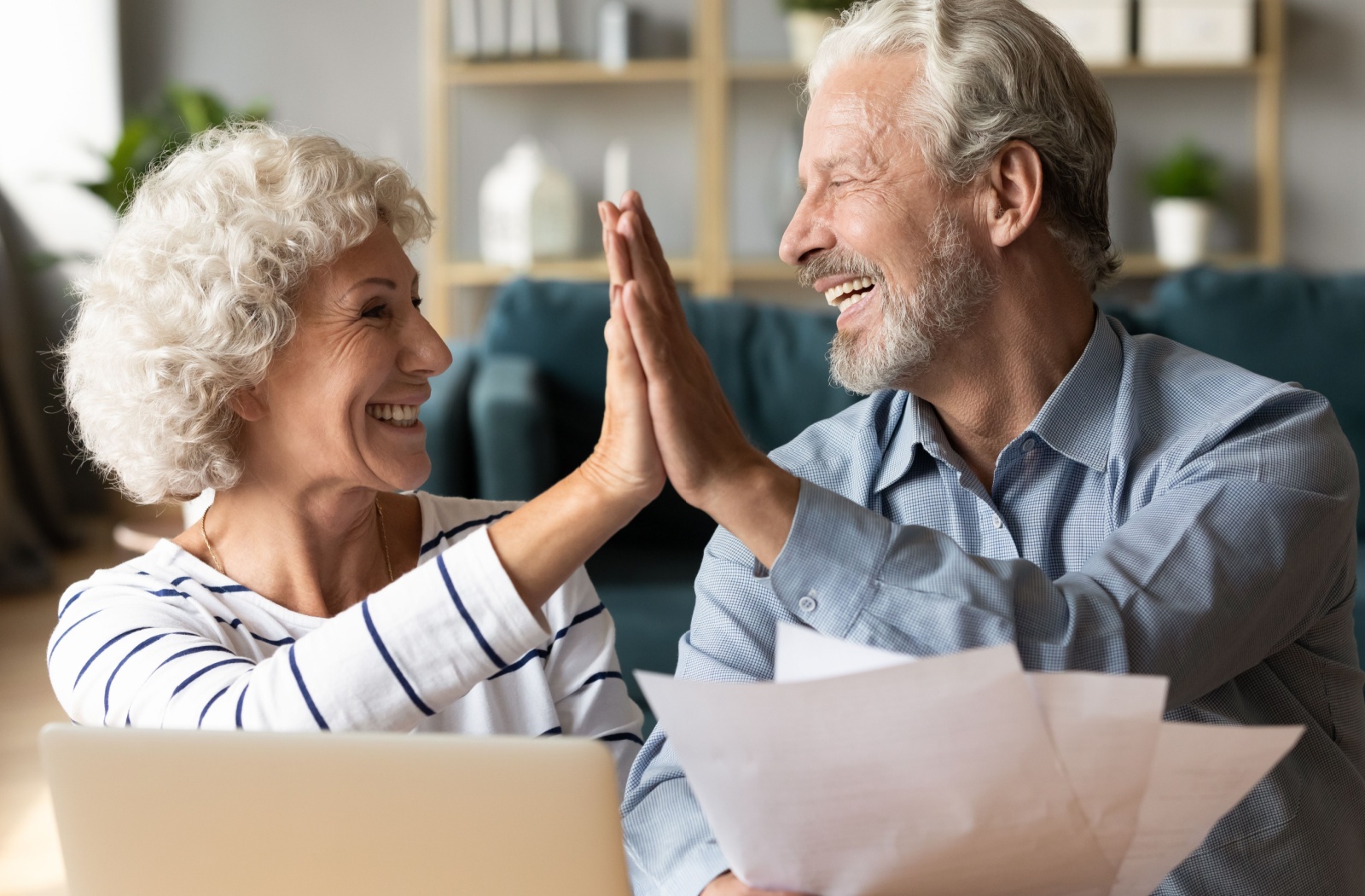 A smiling senior couple high-fives while adjusting their retirement plan.