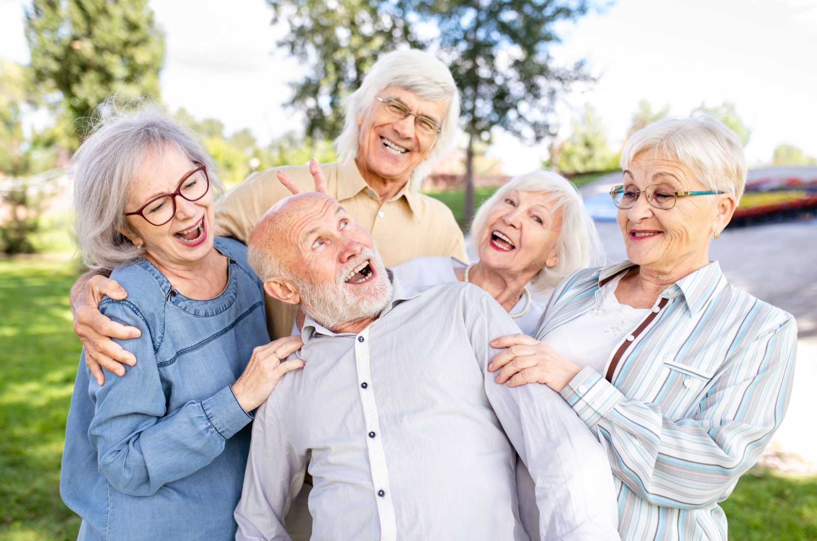 A group of happy smiling older adults enjoying each others company while outdoors.