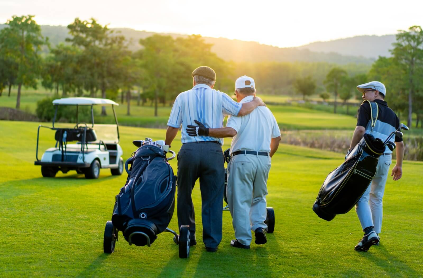 A group of senior golfers are walking on the fairway with their stand bags and cart bags.
